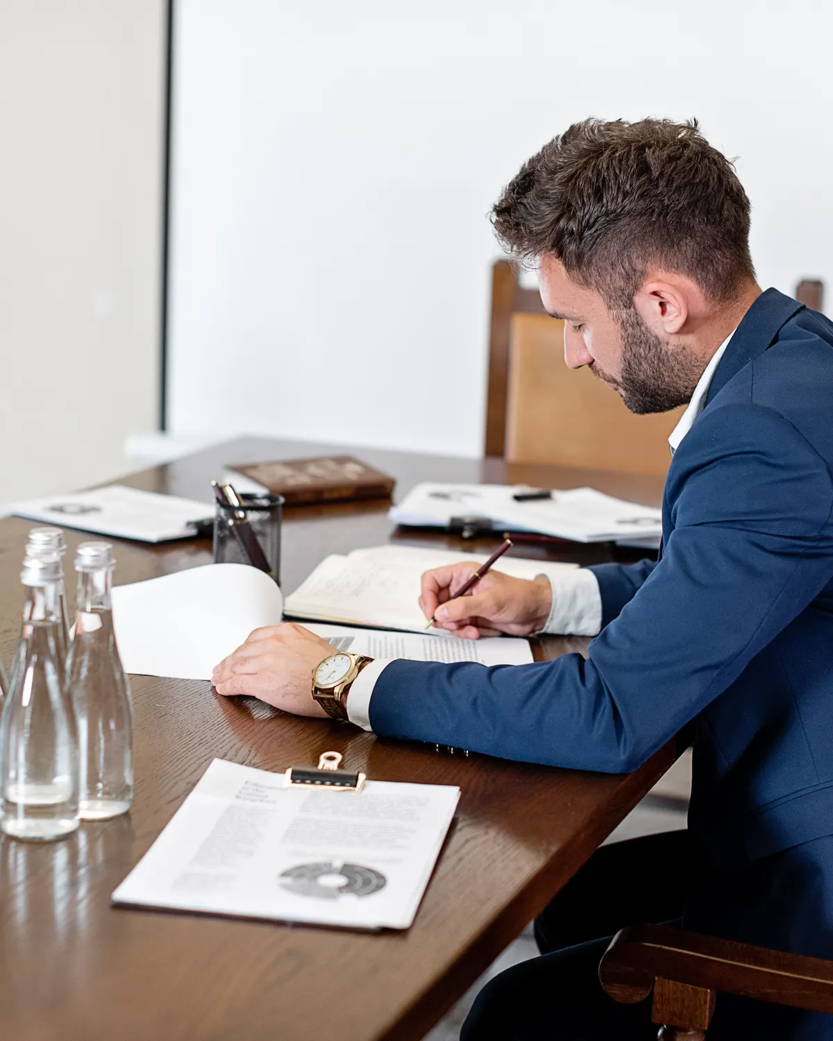 A person in a suit writing notes at a table